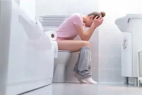 Jovem mulher sentada na sanita, sofre de prisao de ventre. Estás desesperada, com a mão na barriga e outra a segurar a cabeça. Só pensa na escala de bristol e em como resolver este problema. Vai recoorer ao workshop da vera dias coach sobre como ter um intestino saudável, com receitas práticas e deliciosas para deixar de ter prisão de ventre. Podes aceder ao site veradias.coach, separador "Produtos", depois "workshops" e clicas em Receitas para um Intestino Saudável. Faz do teu alimento o teu medicamento através destas receitas